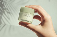 Hand holding facial cream pot, beauty product 