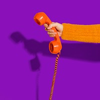 Hand holding rotary phone, purple background psd