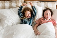 Happy little kids lying on bed
