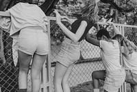 Friendship, women climbing fence, gray photo