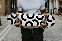 Man holding skateboard, black and white pattern design