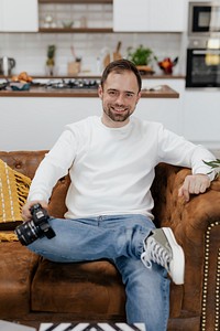 Cheerful man sitting on the couch with a camera