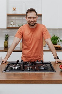 Happy man standing by the stove in the kitchen