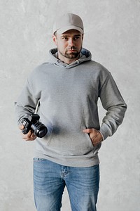 Spy wearing a cap and a hoodie holding a camera