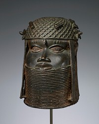 head (male) wearing thick collar up to lower lip; openwork caplike headdress with hanging braids and beaded cords around ears; two "beads" on forehead; flower-like beaded elements at temples--one at PR ear, two at PL ear; open circle at top of head. Original from the Minneapolis Institute of Art.