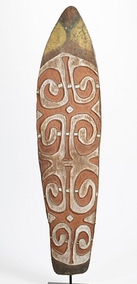 roughly wedge-shaped, slightly curved, with pointed arched top; carved in relief and decorated with dark orange, white and yellow pigments and traces of black pigment; two relief designs on top of one another, each with four corner spiraling loops and two vertical "legs"; handle on back. Original from the Minneapolis Institute of Art.