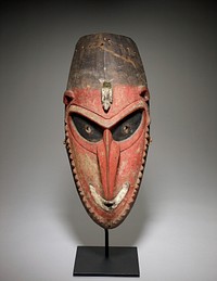 very long, curved-under nose; large upward-slanting black eyes with perforated holes; smiling white mouth with small opening; small "knobs" represent beard; white bird on forehead; high-set ears with two piercings each; red patina on face; brown at top of head; ovoid shape overall. Original from the Minneapolis Institute of Art.