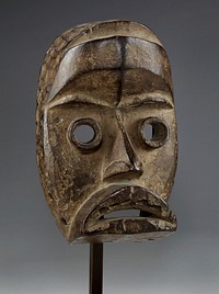 protruding, frowning lips; tubular protruding eyes; thick, pointed nose; t-shaped forehead ridge; medium brown with lighter brown patina. Original from the Minneapolis Institute of Art.