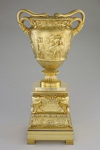 double-handled vase on fluted base; handles are each two snakes with heads resting on rim of vase; relief designs of grapevines, clusters of grapes and leaves; vignette of soldiers and native peoples on each side--soldiers and natives trading guns on one side, natives and soldiers with horses on opposite side; separate square stepped base with scroll and floral designs, coats of arms, tributary text cartouches and high relief elephant heads at each corner. Original from the Minneapolis Institute of Art.