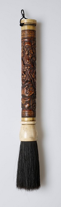 wood handle with bone at each end; black, rather stiff bristles; openwork carving on handle of five men in a grotto with two men on horseback on a path above them; tiger and dragon at top; large trees and bamboo grove; roughly conical bulb housing bristles. Original from the Minneapolis Institute of Art.