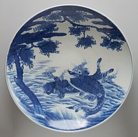 Very large dish with wide ring foot; blue and white; decorated with pair of carp jumping out of water beneath a blooming cherry tree; four vignettes with fish on exterior, with dart-like pattern around foot; underglaze cobalt decor on porcelain. Original from the Minneapolis Institute of Art.