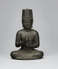 Figure seated with legs crossed and feet on knees; both hands loosely clenched in fists, with PR hand on top, and PL thumb held up into PR fist; hexagonal hat; long earlobes; arms detach. Original from the Minneapolis Institute of Art.