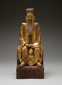 seated elderly man with a long pointed beard and elongated earlobes, with eyes nearly closed; hands in lap; feet flat on floor; man wears a gold robe with long black tie beneath his bears, a cap with flap on the back, red slipper shoes and white socks. Original from the Minneapolis Institute of Art.