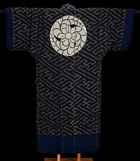 thick, padded kimono; grey and black geometric design on torso and sleeves; grey and black multi-directional diagonal stripe pattern with grey clockwise swastikas connecting grey lines; indigo lining throughout interior; indigo bands around sleeve ends and bottom; indigo rectangles at bottom of front opening flaps; large off-white circular design of flower and spiraling leaves on upper back; katazome technique. Original from the Minneapolis Institute of Art.