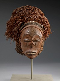 Mask, Chokwe, Mwana Pwo, about 1910. Wood, braided and netted raffia headdress, white beads. mask, H.7-1/4 in. Headdress H.10-1/2 x W.10-1/2 in. Masoji-scarification marks in form of tears below each eye. Tshingelyengelye-cruciform mark with circular terminations in center of forehead. Portion of earlobes missing just below where ears were pierced.. Original from the Minneapolis Institute of Art.