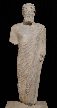 life-size carved statue of a bearded votary; In the archaic Cypriote style. The features show the mixed oriental style transformed by Hellenic influence; His head bears a wreath of leaves and berries permitting rows of small curls to frame his forehead. The beard is rendered in four stiff rows of curls. The skin tight tunic has no pleats, and the cloak which falls from the left shoulder is thrown over the left arm. Beard slightly defective. strong frontality and Greek 'archaic' smile. Original from the Minneapolis Institute of Art.