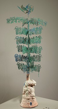 base with iridescent light green glaze and 2 animals, one standing on the back of the other; long post topped with openwork bird finial; 4 long branches at top: 3 depict figures dancing and holding objects and a figure under a canopy on top of branch and figures and radiating coins below branch; one depicts same scene except an animal replaces the figure under canopy; 20 rectangular branches, 19 with figures, horses, deer and figure under canopy with coins sprouting from branches; one with same scene except animal and figure(?) replace figure under canopy; 40 small branches with 3 radiating coins; pendant of monkey with a coin. Original from the Minneapolis Institute of Art.