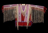 red felt shirt with beaded panels across each shoulder, on upper back and on top of each arm; fringe at edges of beaded panels; open sides with ties; triangular fringed attachments at chest. Original from the Minneapolis Institute of Art.