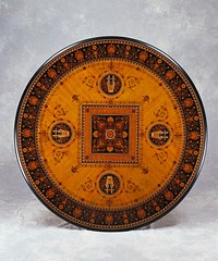 circular inlaid table with four footed pedestal base; central square organic motif with banding of meandering pattern and waves; circular design with harp and wind instruments crossed at center of each side of square; outer band of floral pattern on dark ground. Original from the Minneapolis Institute of Art.