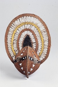 pointed face with bulging white eyes; ovoid headdress with radiating design of alternating linear zigzags and solid color bands or rust red and yellow; wooden pick behind supports face. Original from the Minneapolis Institute of Art.