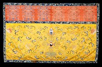Hanging of embroidered imperial yellow satin with an upper valance of brocaded red satin. The central design of the lower portion shows the Yin and Yang symbol emerging from a lotus flower. In the field on either side are large lotus blossoms and trailing branches. The colors include shades of blue, green, coral, mulberry, pink, yellow and tan. Chiefly satin stitch and couching. The brocaded valance carries a row of hanging lanterns with mystic symbol pendants in shades of brown and tan. Around the edge, and separating valance from main field is a band of black satin embroidered with running floral pattern in shades of blue. Lining of yellow cotton. NoteA.P. thinks brocade may be later than early 18th century.. Original from the Minneapolis Institute of Art.
