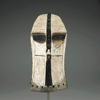 mask carved on flat rectangular planes; median crest and nose drilled at regular intervals with small cavities containing traces of symbolic materials; tufts of hair implanted in nostrils; white and black highlights; intricately grooved surface. Original from the Minneapolis Institute of Art.