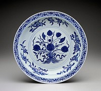 Blue and white bowl with small lip; bouquet of lotus flowers at center with fruits on stems around edge; chased foliage on rim; waves with flying bats around outer edge. Original from the Minneapolis Institute of Art.