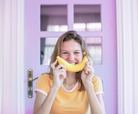 Happy Caucasian woman with banana on her face