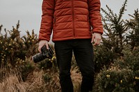 Photographer wearing jacket, holding camera, nature photo