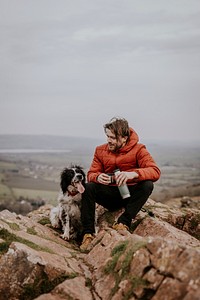 Man sitting with dog on mountain photo