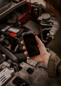 Man with broken car, holding phone photo