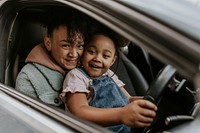 Daughter sitting on mother's lap in a car