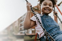 Happy African girl on playground swing