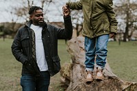 Dad holding daughter's hand, walking on tree stump