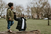 Dad holding daughter's hand, walking on tree stump