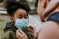 Mother putting mask on child, COVID-19 photo