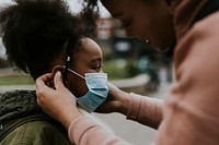 Mother putting mask on child, COVID-19 photo