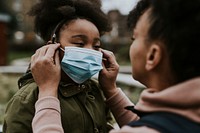 Mother putting mask on child, COVID-19 photo