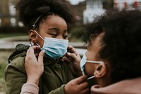 Mother and child putting on mask, COVID-19 photo