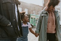 Happy black family walking daughter in city