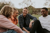 Cheerful diverse friends hanging out, sitting in a park