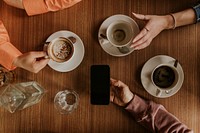 Man holding smartphone, coffee cups on table