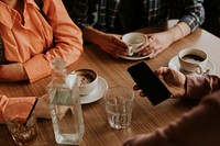 Man holding smartphone, coffee cups on table