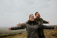 Couple spreading arms on mountain