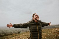 Happy man spreading arms on mountain