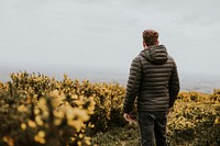 Man wearing jacket on flower field, back view