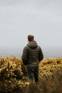 Man wearing jacket on flower field, back view