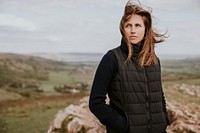 Woman in black puffer vest standing on mountain photo