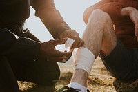 Man putting bandage on friend's leg photo