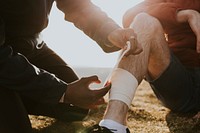 Man putting bandage on friend's leg photo